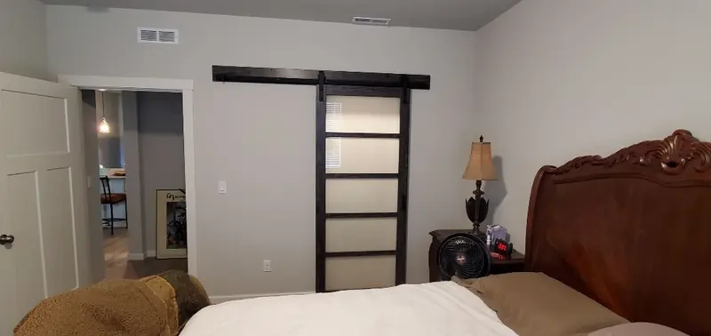 Sliding barn door with a black frame and frosted glass panels in a bedroom