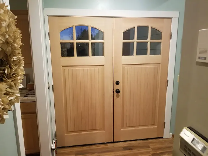Pair of light wood doors with arched divided-light windows, seen from inside