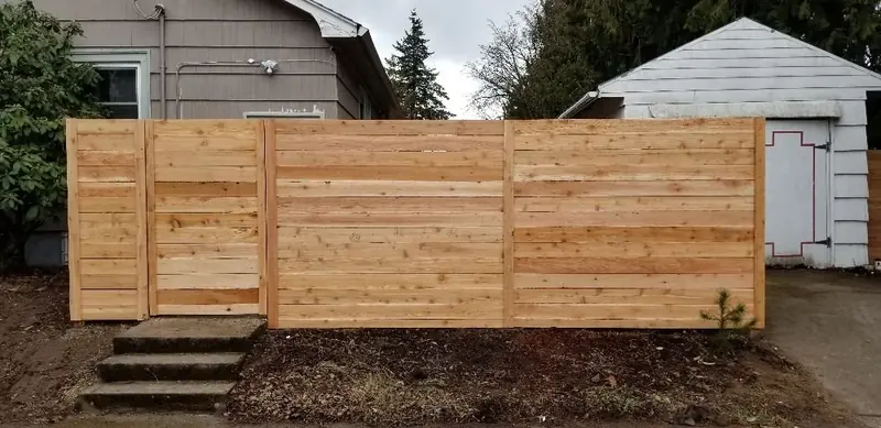 Horizontal-board cedar fence with wood steps in front, across a backyard