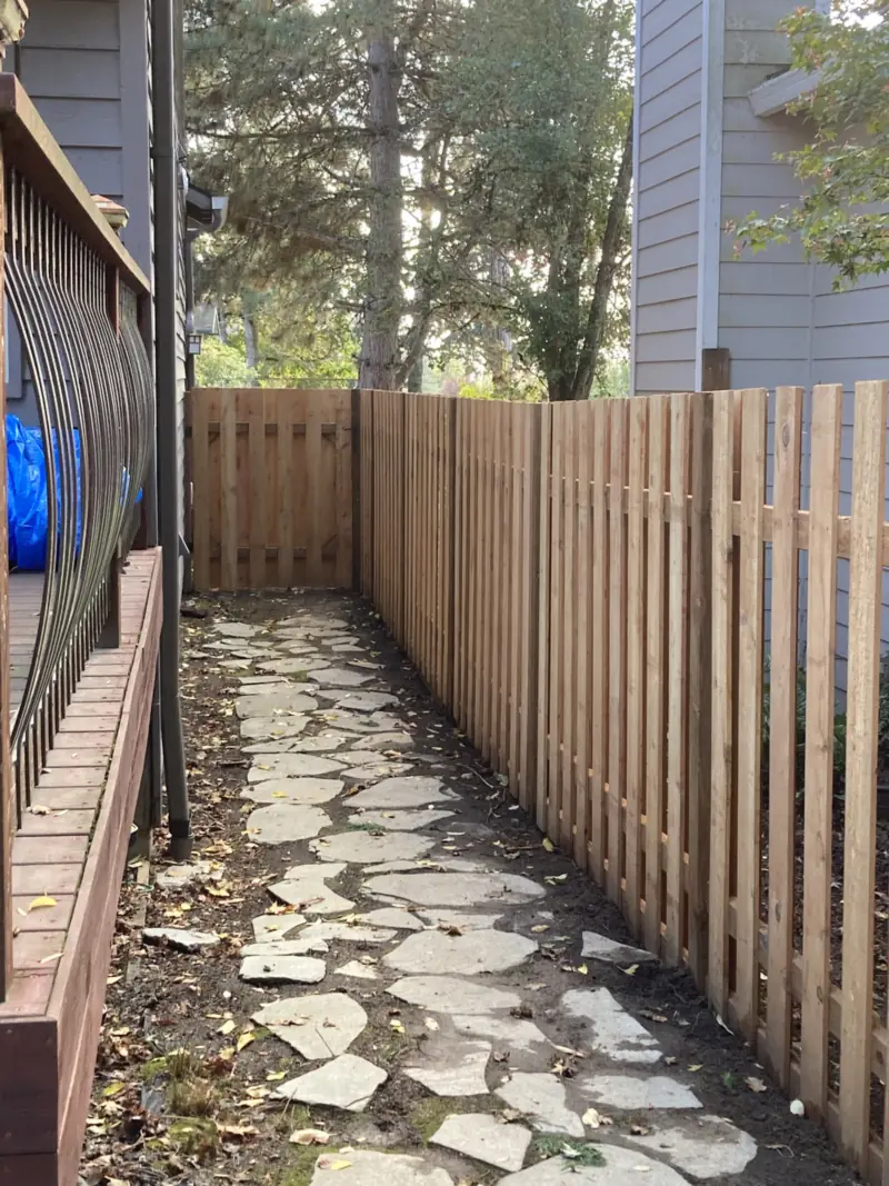 Cedar picket fence running along a flagstone side path