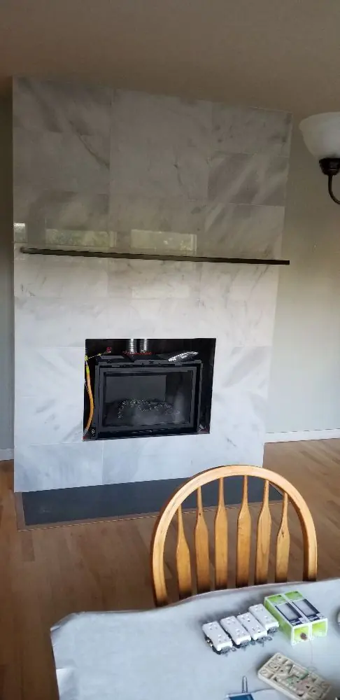 Floor-to-ceiling marble-look tile fireplace surround with a slim black mantel shelf