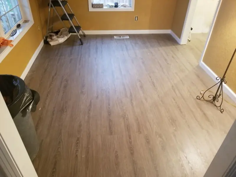 Wood-look vinyl plank floor across an empty room with warm yellow walls