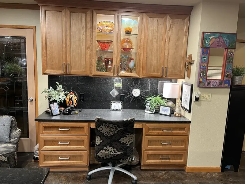 Built-in kitchen desk with drawers and glass-front upper cabinets in matching wood