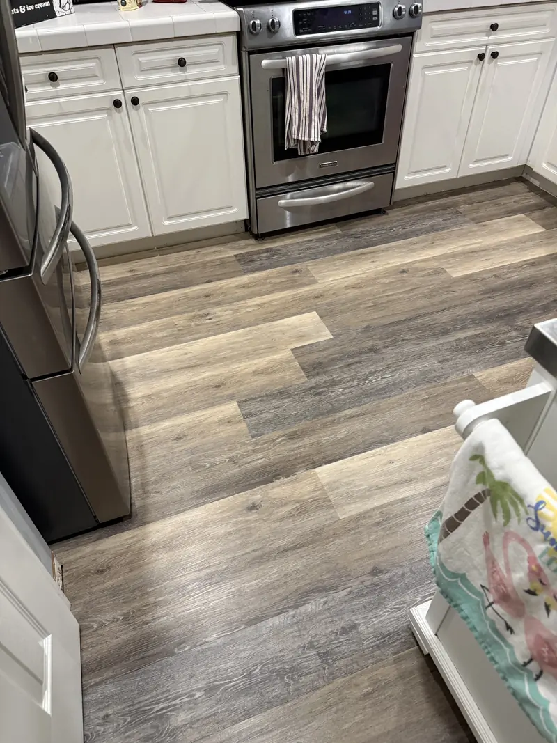Wood-look plank flooring in a kitchen with white cabinets and a stainless range