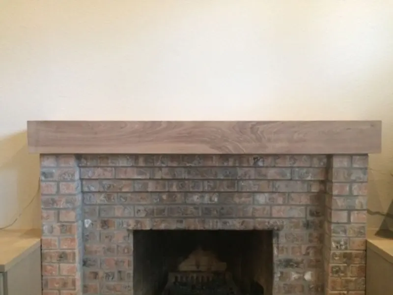 Rustic wood beam mantel above a brick fireplace