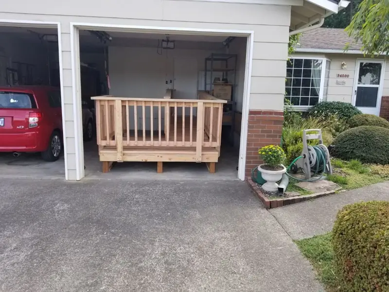 Wood access ramp with railings built inside an open garage, seen from the driveway