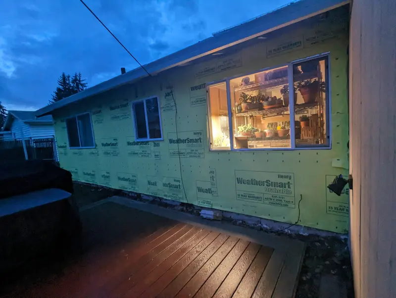 House wrapped in WeatherSmart house wrap at dusk, with new windows lit from inside