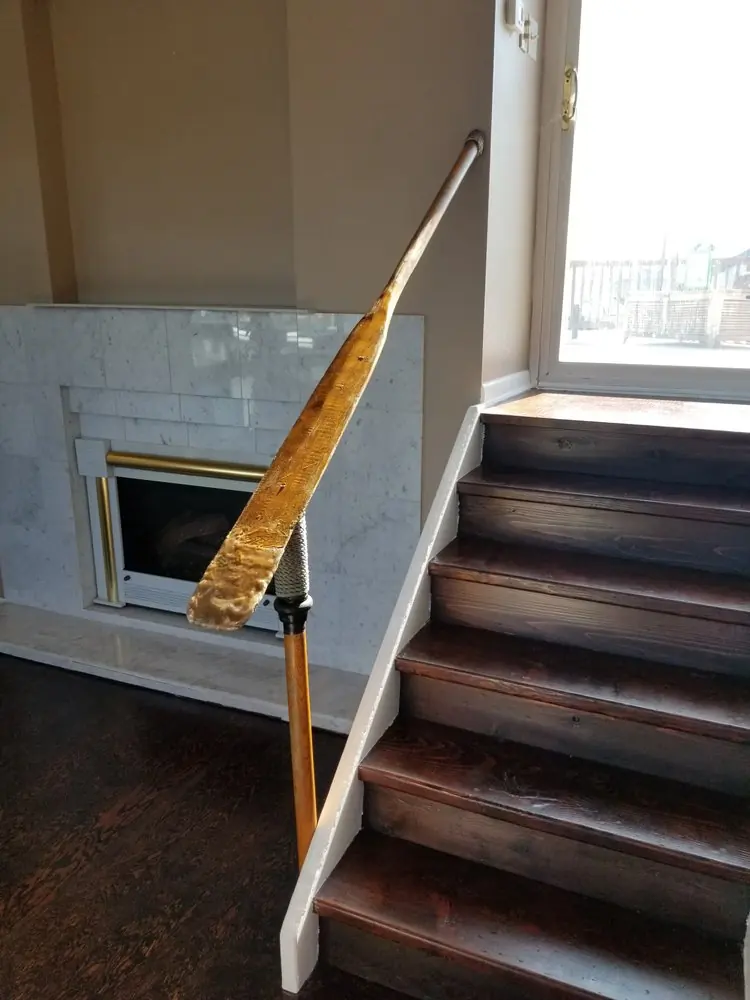 Vintage wooden oar mounted as a handrail beside dark-stained stairs