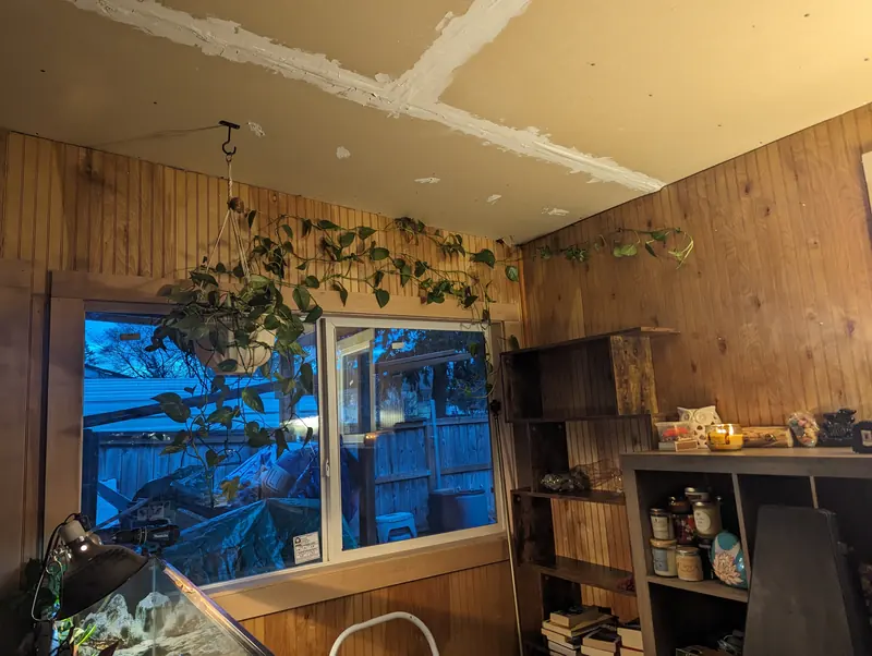 New sliding window in a wood-panelled room, with newly taped ceiling drywall above