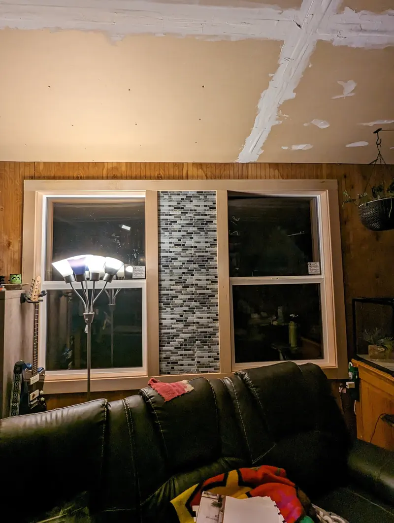 Two new windows either side of a mosaic-tile column in a wood-panelled living room